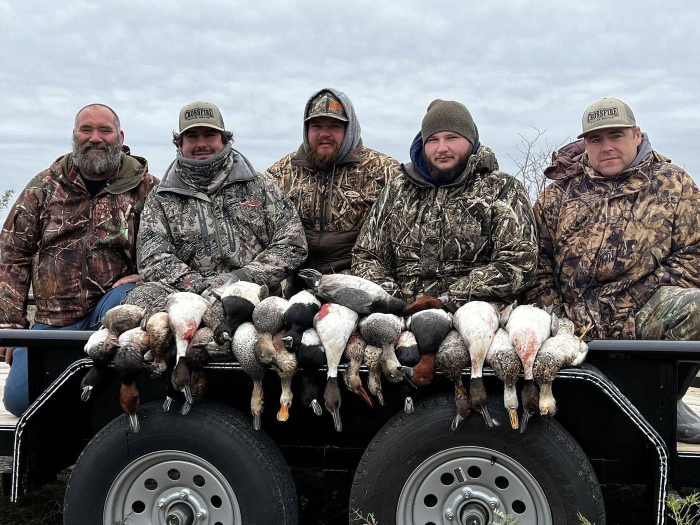 Five hunters kneeling behind a trailer of Central Texas ducks