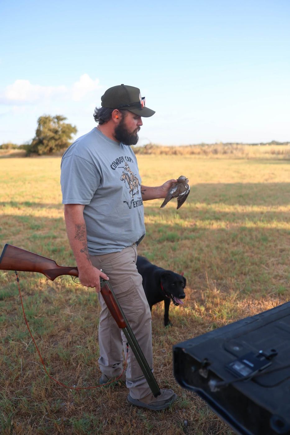 Hunter holding a dove in an open Central Texas field