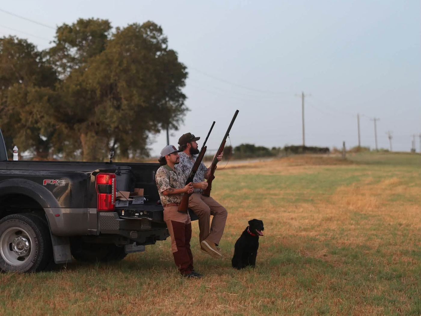 Dove hunter and retriever at the truck in an open Central Texas field at golden hour
