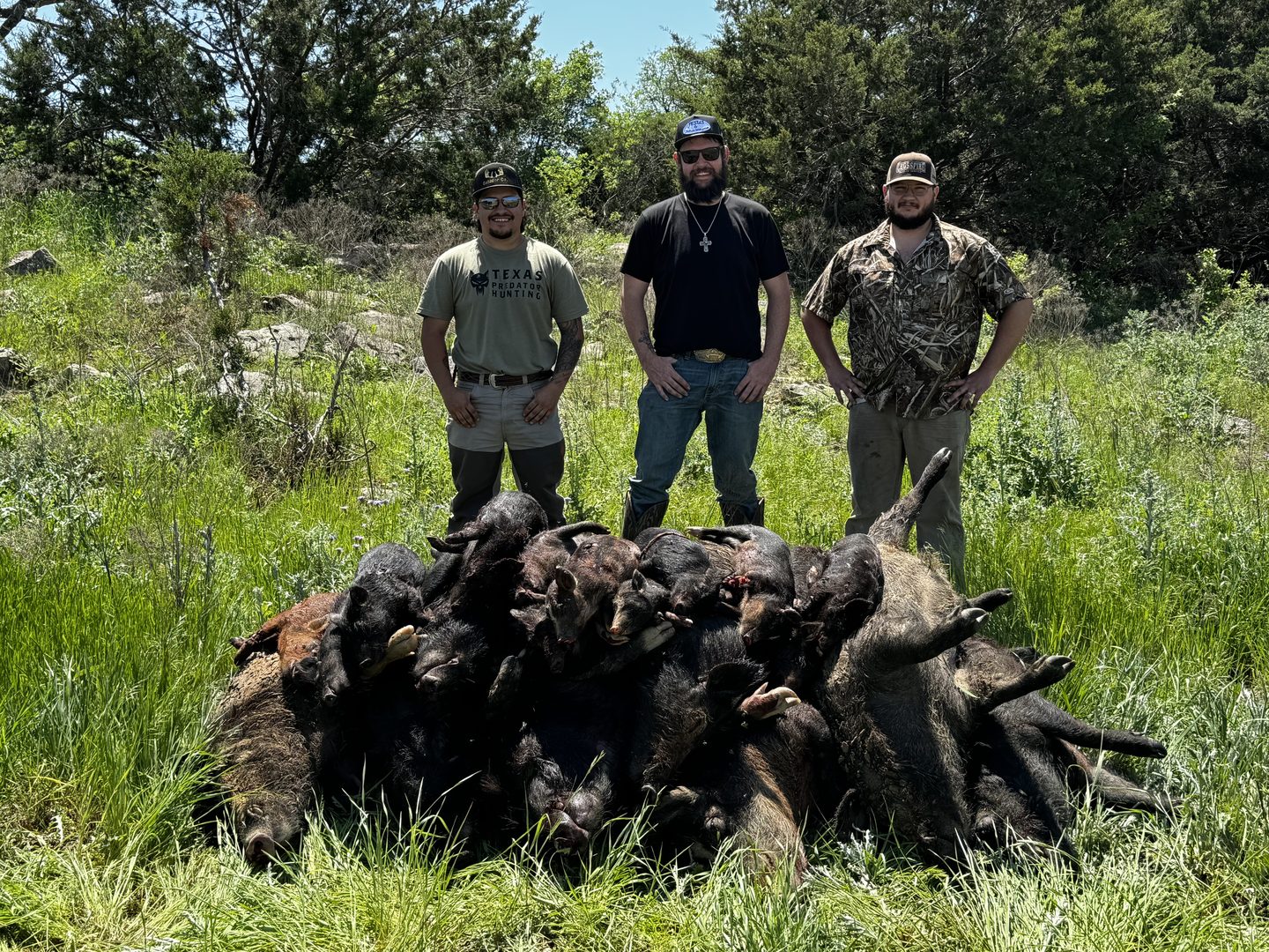 Three hunters standing behind a pile of hogs taken on a guided hunt near Dublin, Texas
